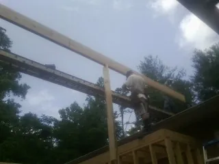 Carpenter setting a ridge beam over a new addition frame — Ice Dam Removal by Roofing Brothers in Higden