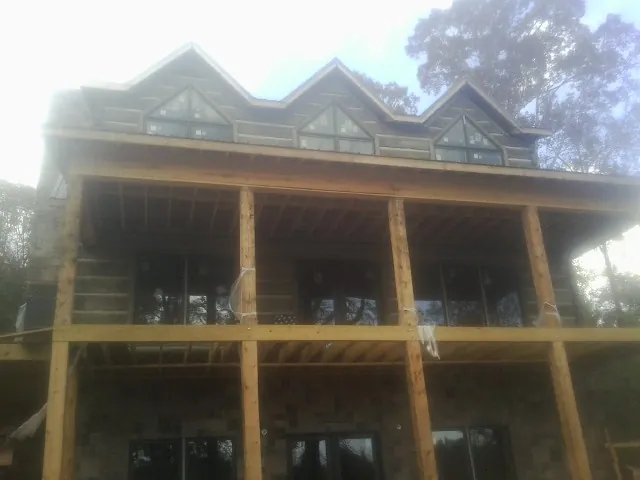 Dormers and porch framing on a large log home under construction — Roof Coating work by our crew in Higden