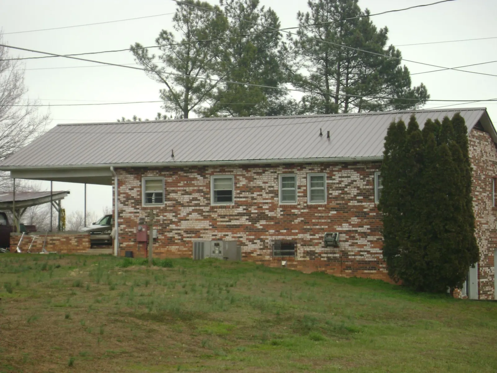 Gray metal roof on a brick split level home with a carport in Higden
