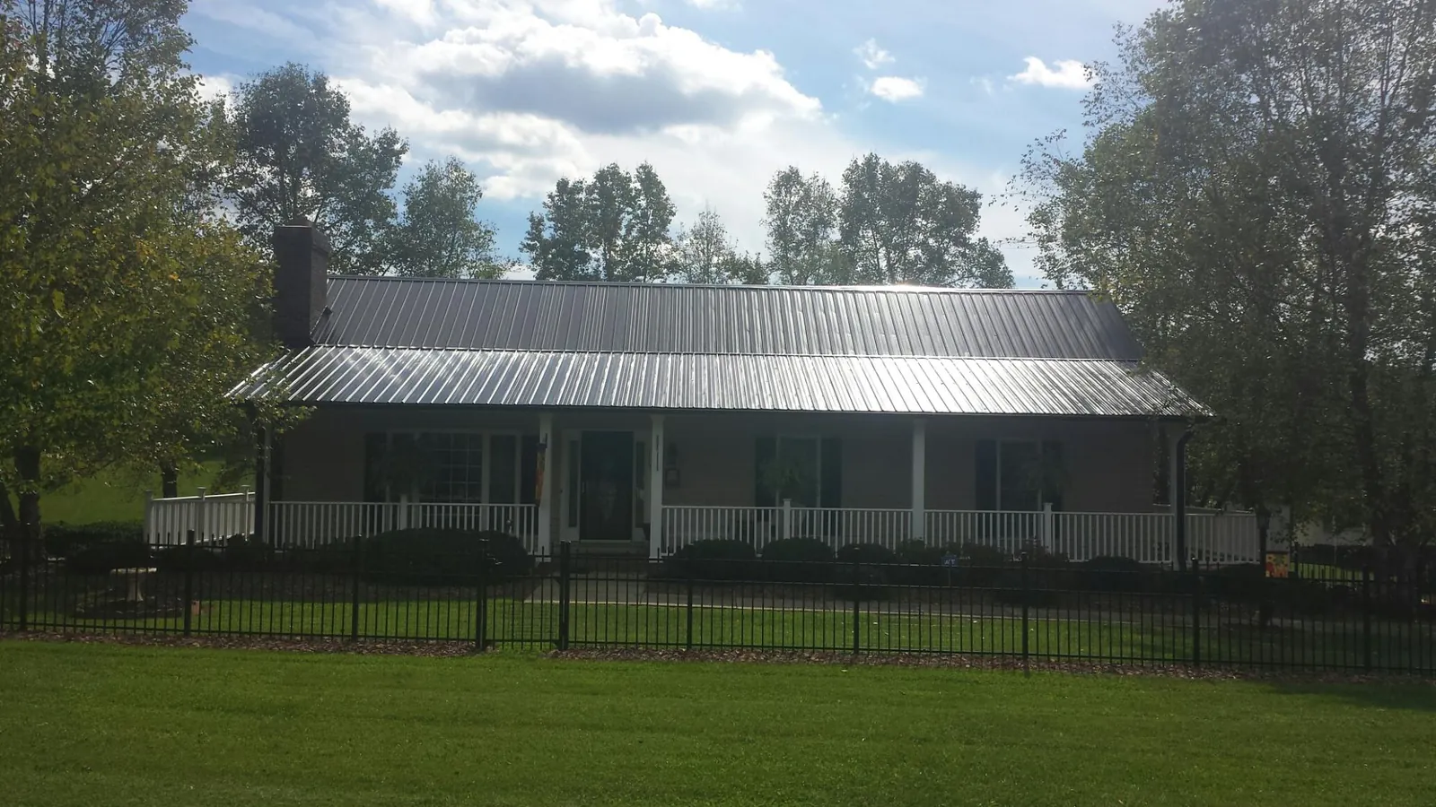 Gray metal roof on a brick ranch with a full width front porch — Gutter Guard Installation work by our crew in Higden