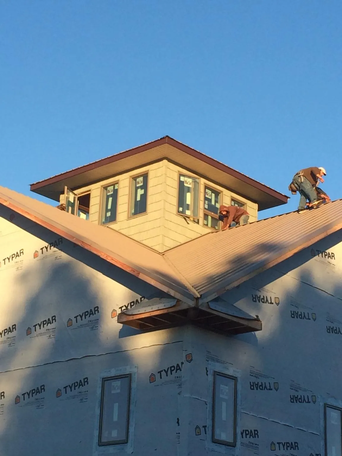 Roofers working around a rooftop cupola on a new metal roof at sunset — Roof Waterproofing in Higden by Roofing Brothers